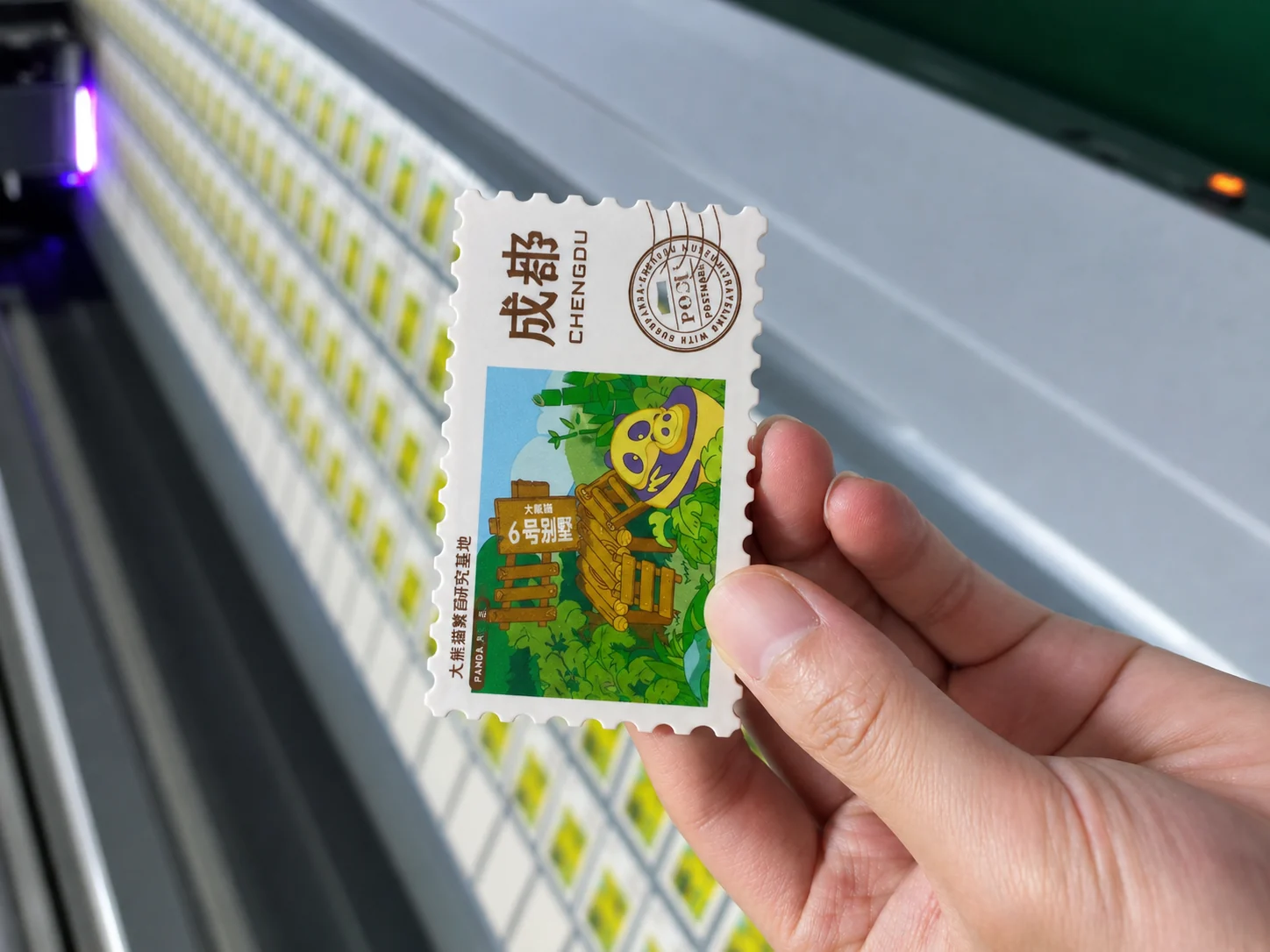 ABS fridge magnet sample held beside UV printing production equipment